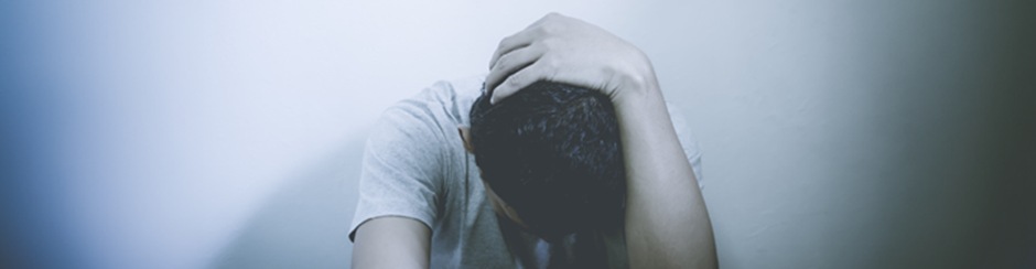 Young man holding head in hands