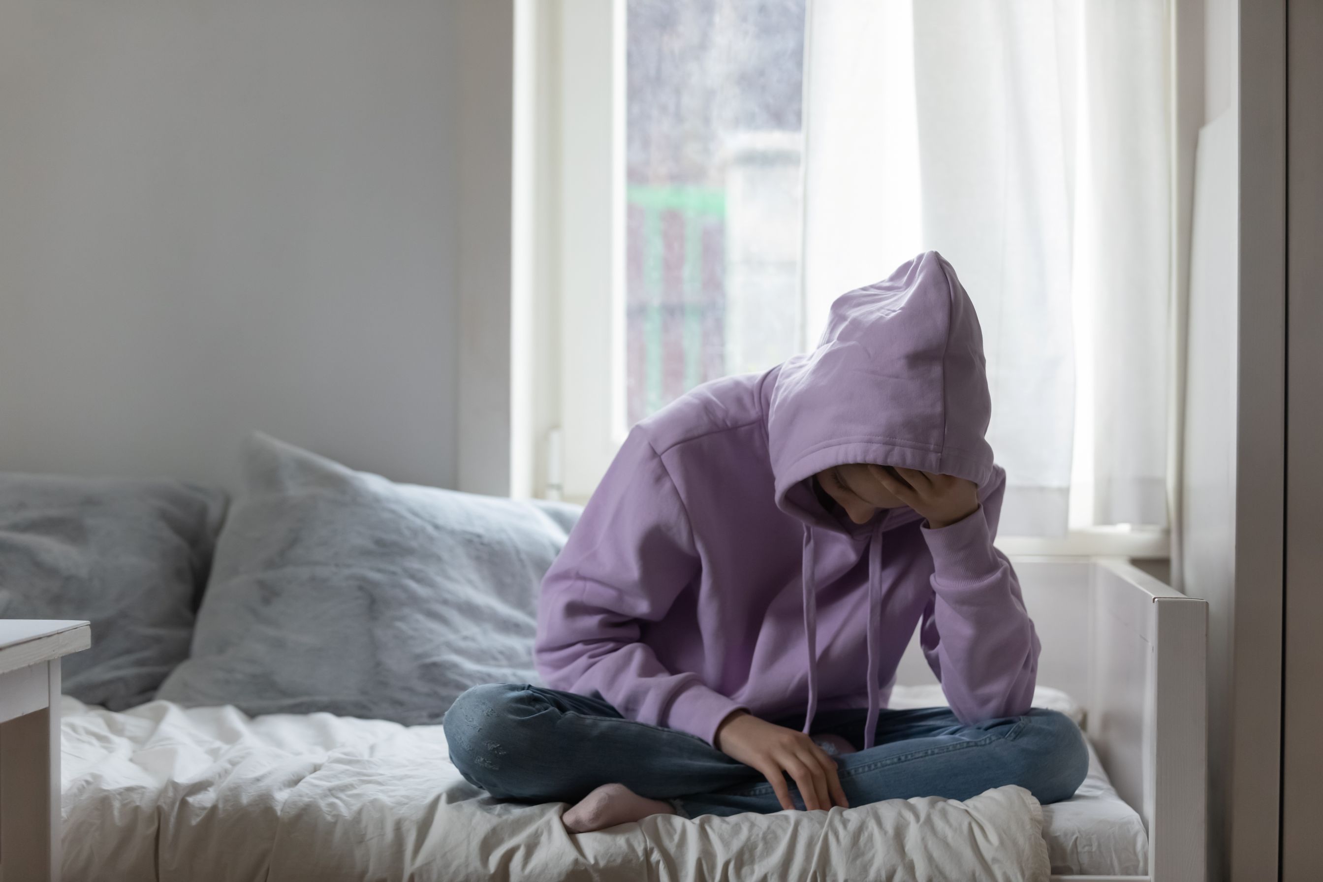Man sitting on bed, depressed