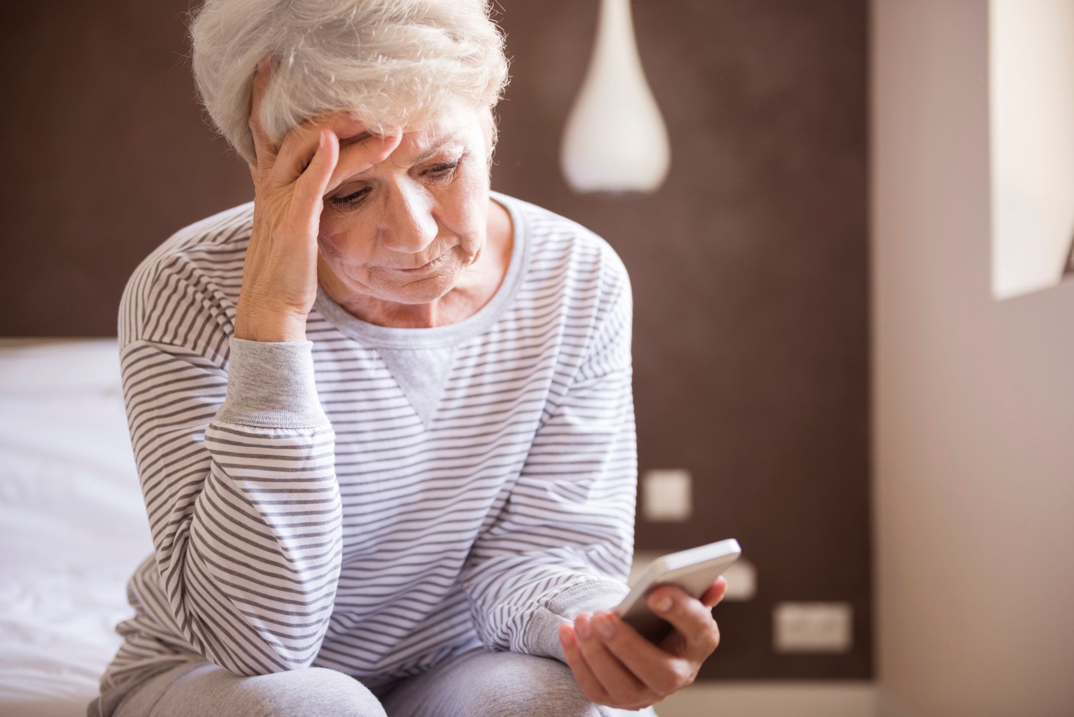 Woman sitting on bed looking at phone